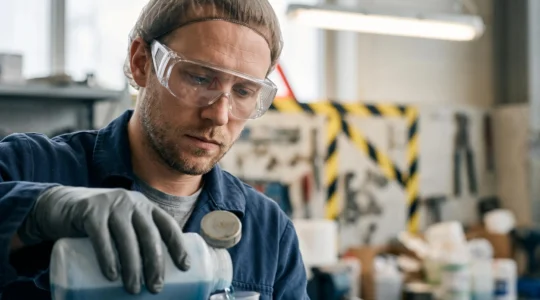 Portrait rapproché d'un opérateur industriel portant des lunettes de protection juste avant une manipulation de produit chimique